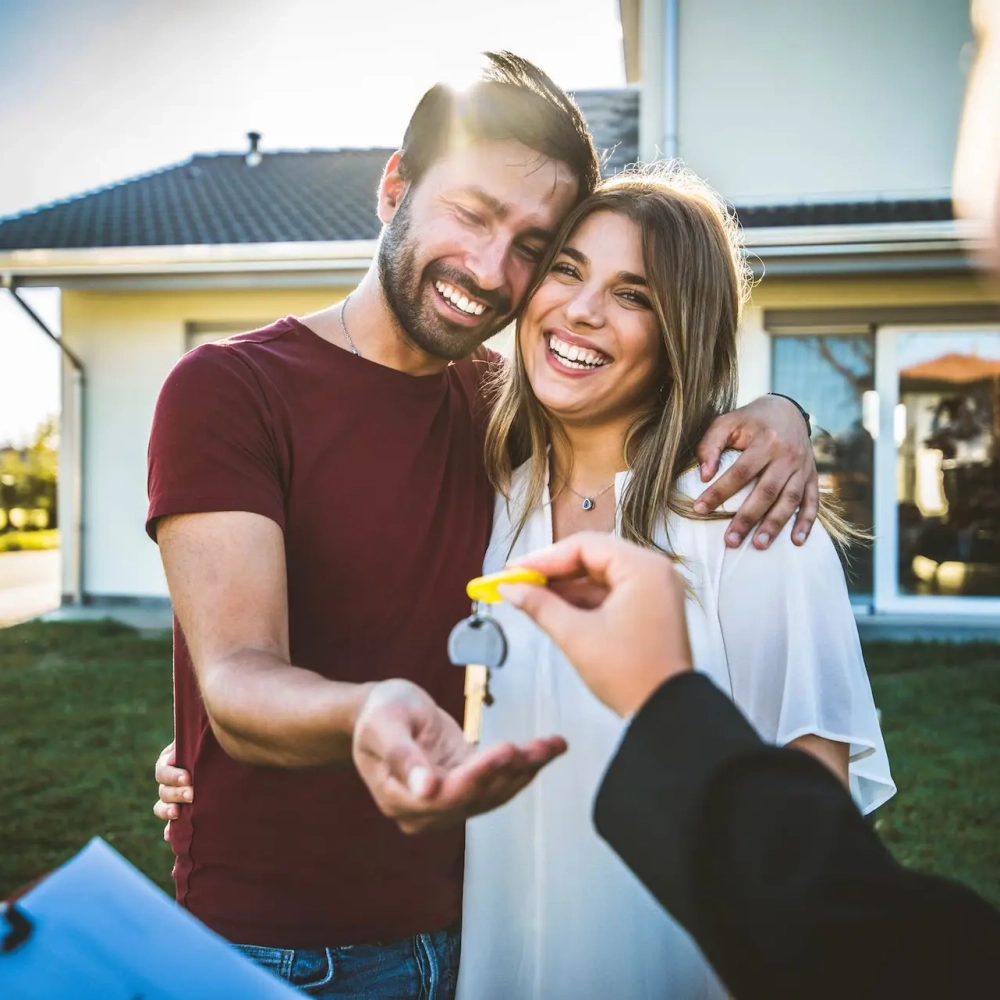 Happy millennial couple receiving keys from realtor, purchasing real estate - Family meeting with real estate agent - New house and real estate concept